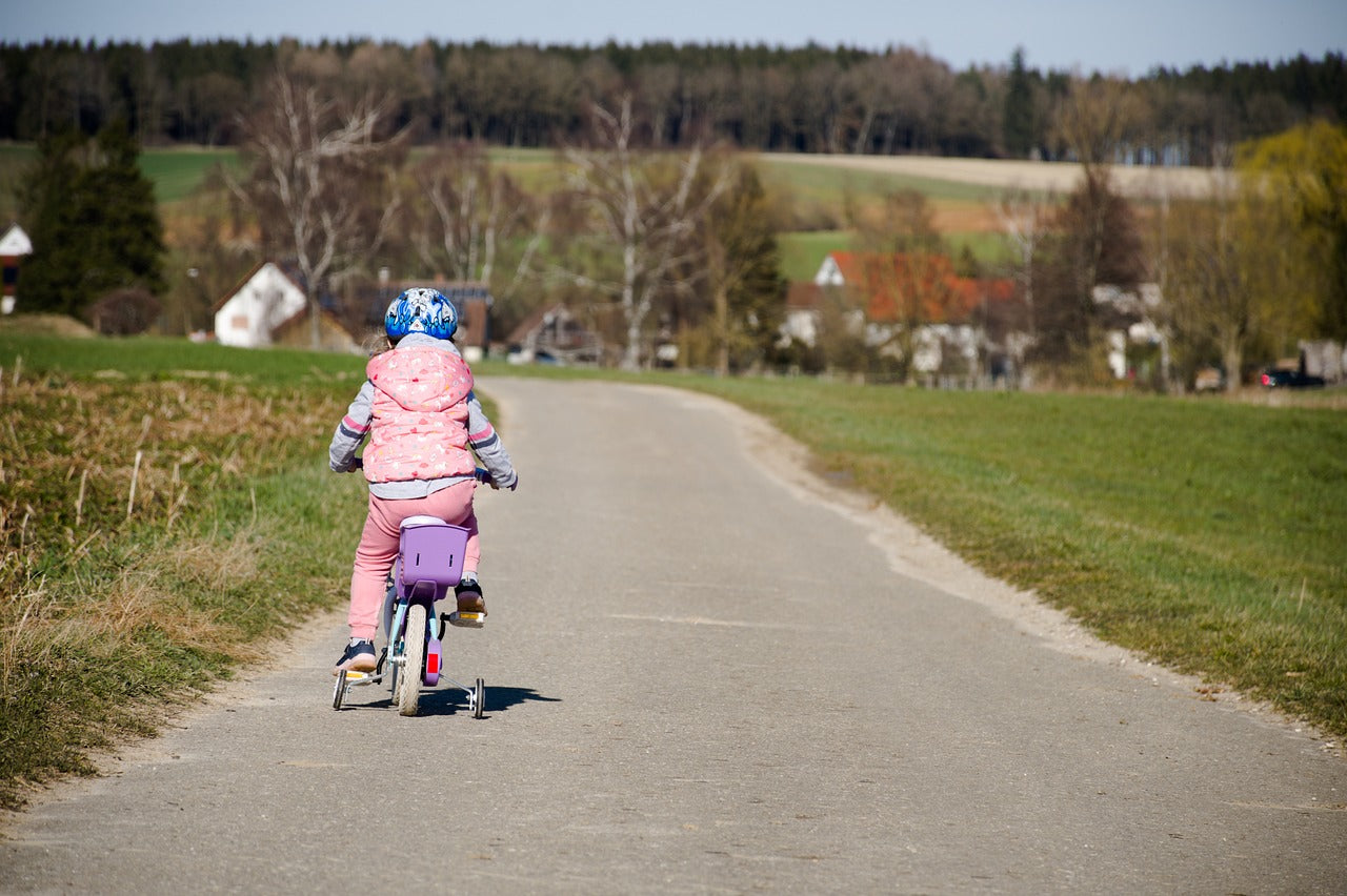Enfant apprenant le vélo en sécurité, travail de l’équilibre et du freinage, vélo à taille adaptée pour poser les pieds au sol et prendre confiance rapidement.